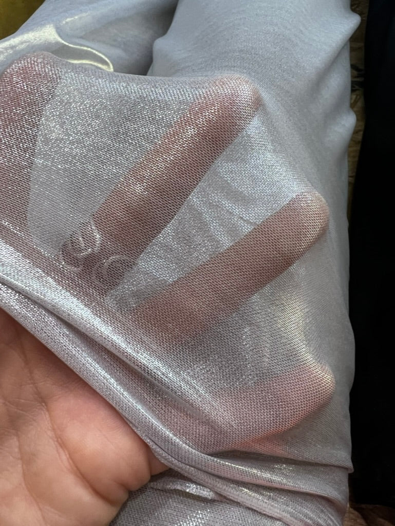 A close-up of a hand holding sheer, shimmering fabric with a metallic silver-gray sheen.